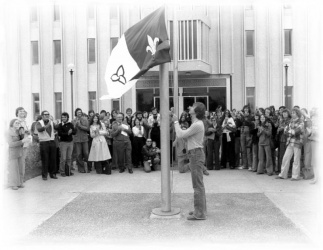 Michel Dupuis qui hisse le drapeau franco-ontarien devant l'Université de Sudbury le 25 septembre 1975