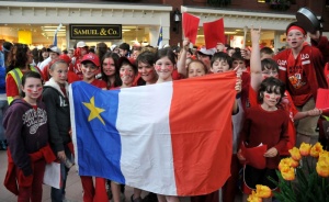 Jeunes participants déployant fièrement le drapeau acadien lors des Jeux de l'Acadie à St-Jean (N.-B.), 2010